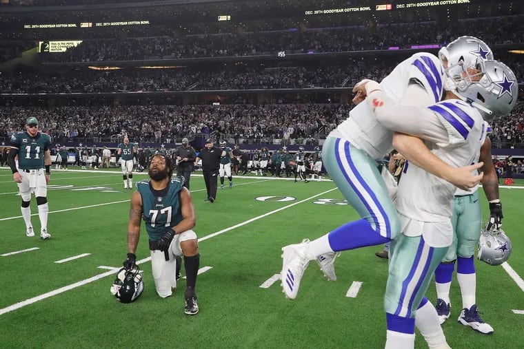 Dallas quarterback Dak Prescott, right, and teammate Cooper Rush celebrate as Eagles defensive end Michael Bennett kneels after the Cowboys win.