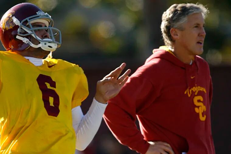 Southern Cal quarterback Mark Sanchez throws the ball as coach Pete Carroll watches during practice Saturday.