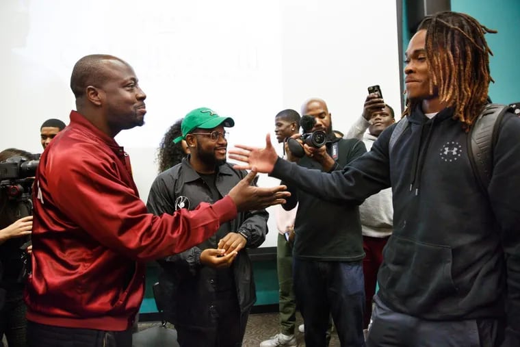 Wcylef Jean, left, acclaimed hip-hop artist and producer, shakes hands with Temple student and athlete .Isaiah Wright after Wright demonstrated his rapping skills for his peers and Wyclef, in a “Hip Hop and Black Culture” class at Temple University