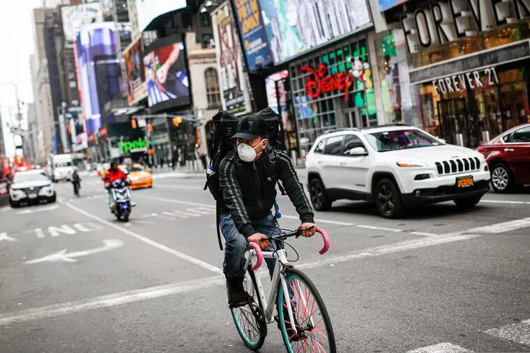 A bicycle delivery worker wears a protective face mask as he rides through a sparsely populated Times Square in New York City.