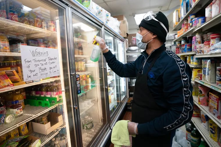 Pedro Reyes, a grocer at Wharton Grocery, cleans doors at the store last month.