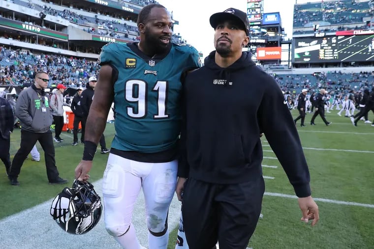 Eagles defensive tackle Fletcher Cox (left) talks to sidelined quarterback Jalen Hurts as they exit the field after the 20-10 loss to the Saints.