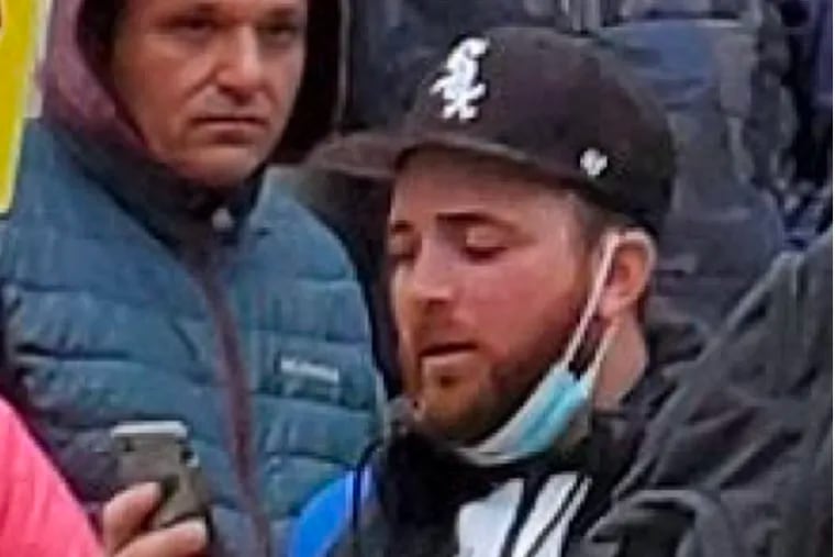 A man federal prosecutors say is Richard Michetti, of Ridley Park, checks his cell phone in a crowd of Trump supporters during the Jan. 6 Capitol insurrection