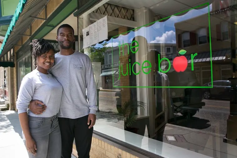 Kelli Mouzon and Seth Amoah stand outside their business, The Juice Bar, in downtown Merchantville, an older Camden County suburb that's attracting new businesses and residents. The couple met while attending Temple University and have since moved to Merchantville.