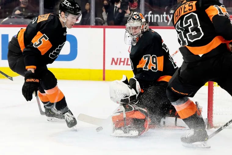 Flyers goalie Carter Hart makes a save against Buffalo on April 11 as Phil Myers (left) and Kevin Hayes rush to assist him.