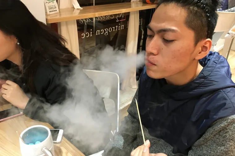 Customer Alkut Galip exhales vapor from the Eskimo kiss dessert prepared with liquid nitrogen at N2 Sweet Cafe in Chinatown.