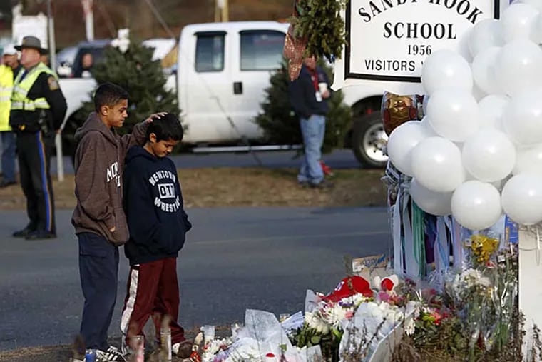 Brothers Thomas, 13, left, and Steven Leuci, 9, pay their respects at a memorial for shooting victims near Sandy Hook Elementary School, Saturday, Dec. 15, 2012 in Newtown, Conn.  A gunman walked into Sandy Hook Elementary School in Newtown Friday and opened fire, killing 26 people, including 20 children. (AP Photo/Jason DeCrow)