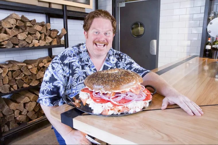 Host Casey Webb poses with Spread Bagelry's 13-pound Classic Whale Challenge, as seen on Travel Channel's Man v. Food.