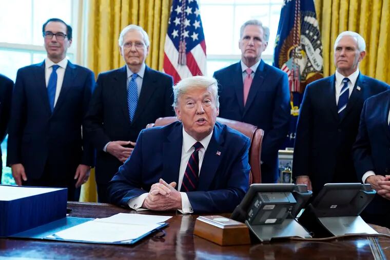President Donald Trump speaking at a late-March White House bill signing ceremony, with (from left to right) Treasury Secretary Steven Mnuchin, Senate Majority Leader Mitch McConnell, House Minority Kevin McCarthy and Vice President Mike Pence behind him.