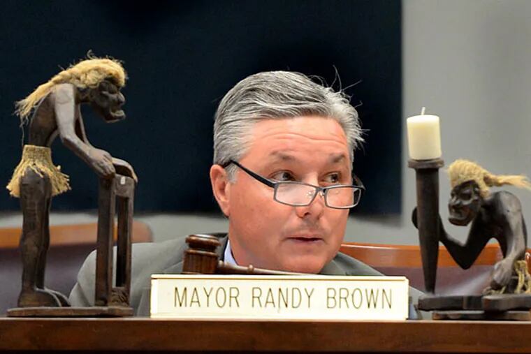 Evesham Mayor Randy Brown presides over a council meeting with his tiki figurines prominently displayed. TOM GRALISH / File  Photograph