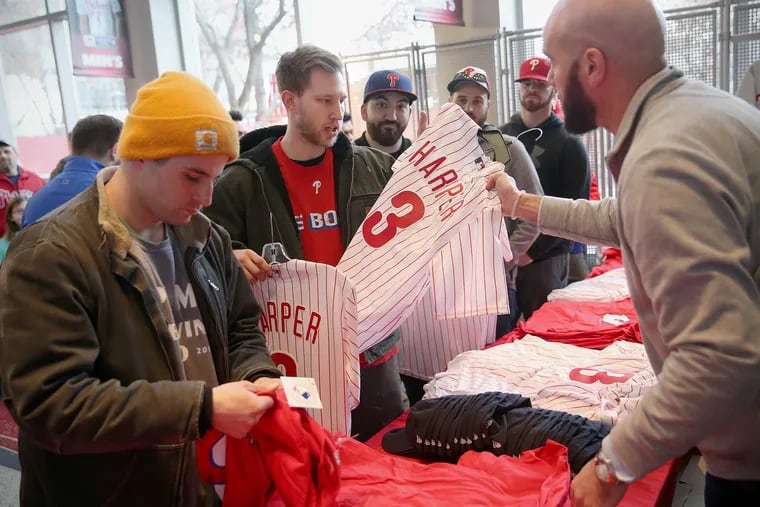 Retail manager Francis Winkey, right, hands a Bryce Harper jersey to Eric Bowen of Prospect Park, Pa., inside the Phillies team store at Citizens Bank Park in South Philadelphia on Saturday, March 2, 2019. The store immediately began selling Harper t-shirts and jerseys after his introduction in Clearwater, Fla.