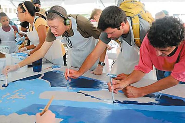 Jordan McCullough (left), 21, Philadelphia, Michael Germaeraad, 22, California, and Steve D'Aprile, 52, Audubon, paint a template for the newest mural in the Philadelphia Mural Arts Program, "How We Fish: A Mural About Work," on Labor Day 2012.  (Clem Murray / Staff Photograph)