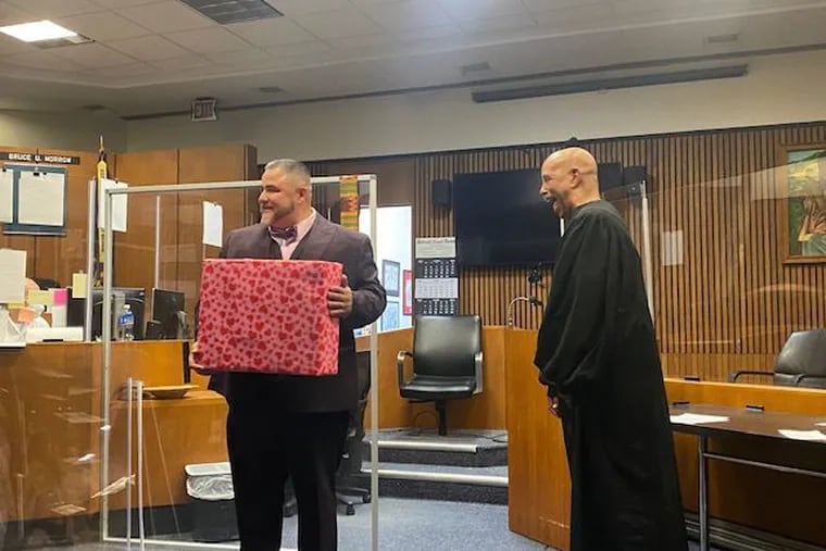 Edward Martell, left, holds a monogrammed briefcase given to him by his law firm after he was sworn in as a lawyer by Judge Bruce Morrow, his mentor.