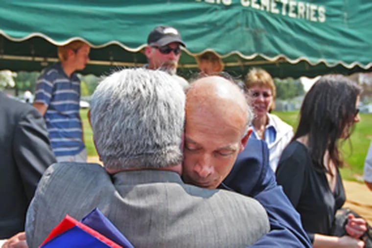 Joe Crescenz, brother of Medal of Honor winner Michael Crescenz, embraces a family friend at a ceremony marking his sibling&#0039;s disinterment from Holy Sepulchre Cemetery for a move to Arlington National Cemetery this month. He holds a flag given to him by a Vietnam veteran.