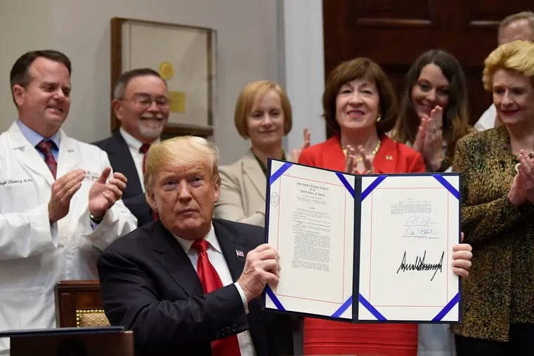 President Donald Trump held up the 'Patient Right to Know Drug Prices Act' after signing it and the 'Know the Lowest Price Act of 2018,' during a ceremony in the Roosevelt Room of the White House on Oct. 10, 2018. These bills, which were sponsored by Sen. Susan Collins, R-Maine, in red, and Sen. Debbie Stabenow, D-Mich., right, help protect Medicare patients and those with private insurance from overpaying for prescription drugs by outlawing pharmacy "gag clauses."
