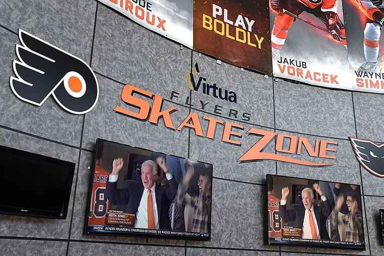 In the lobby of the Flyers Skate Zone in Voorhees, the large screen television monitors have Comcast Sports Net on with coverage of the death of Flyers owner Ed Snider, who died of bladder cancer at age 83 April 11, 2016.  On the monitors, Ed Snider is shown cheering on one of his teams.