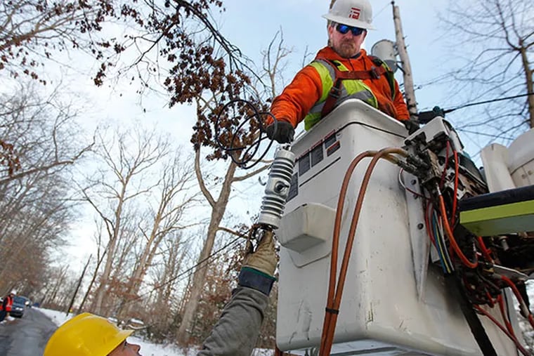 Jim O'Hara, in the bucket, reaches for a cutout that is being handed to him by Chris Sansone. They are linemen for Foley Electric in Brick, NJ, and are replacing a transformer on Waynesborough Road in Paloi, PA.  ( MICHAEL BRYANT / Staff Photographer )