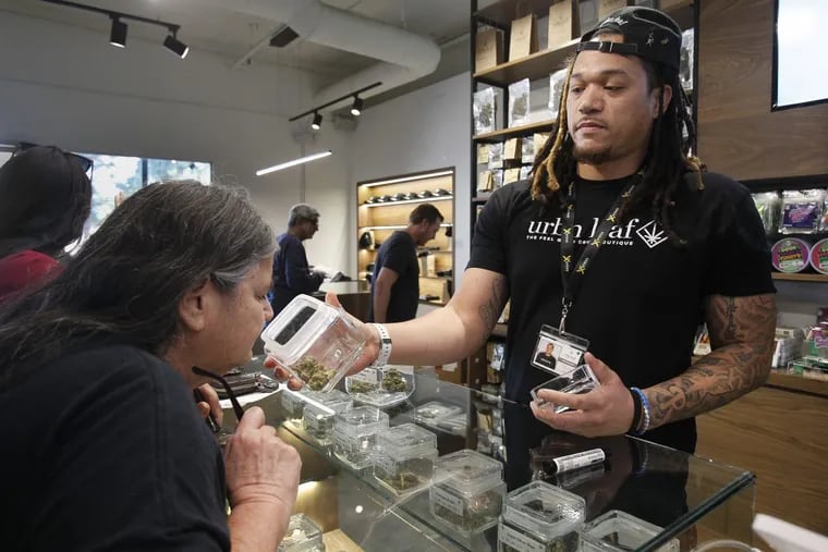 Kerry Durrell, 61, inspects marijuana held by budtender Pierce Hunter at Urbn Leaf in California. Pennsylvania is considering adding the sale of similar plant material in dispensaries.