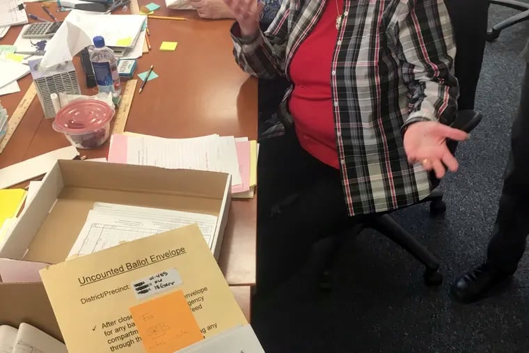 This Nov. 23, 2018 photo shows Alaska State Review Board ballot examiner Stuart Sliter reacting when a loose ballot from a tied state House race is found without an envelope in Juneau, Alaska. Officials are investigating the origin of the ballot and will decide by Friday, Nov. 30, whether to count it during a recount of the Fairbanks House District 1 race. (James Brooks/Anchorage Daily News via AP)