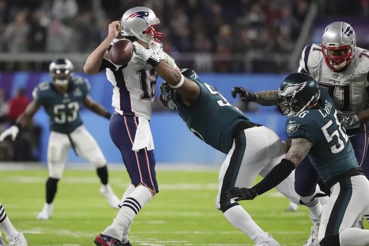 In a huge fourth-quarter play, Brandon Graham knocks the ball out of Tom Brady's hand as defensive end Chris Long moves in. Derek Barnett recovered the fumble. DAVID MAIALETTI / Staff Photographer