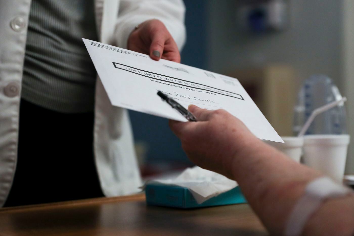Julia Dewey, a second-year medical student and volunteer with JeffVotes, hands Ruth Edwards an absentee ballot.