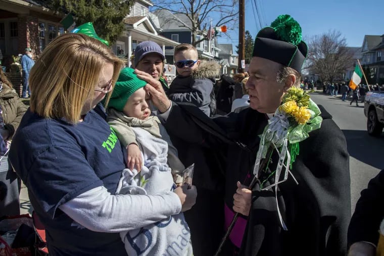 Beau Seedes, 21-months-old, who has a rare form of muscular dystrophy, is blessed by Monsignor William Hodge, pastor of St. Mary’s Church, Gloucester City, during the 2nd annual Gloucester City St. Patrick’s Day Parade March 5, 2017. The Seedes — mom Lori is holding Beau with dad Brian holding brother Braeden, 4 — live in Gloucester City.