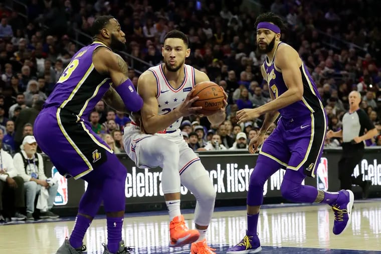 Ben Simmons drives to the basket past LeBron James (left) and JaVale McGee.