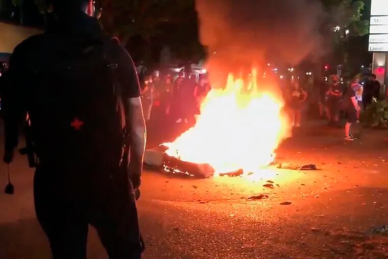 In this image taken from video, a mattress burned on a street near the Portland Police Bureau's North Precinct on Sept. 6.