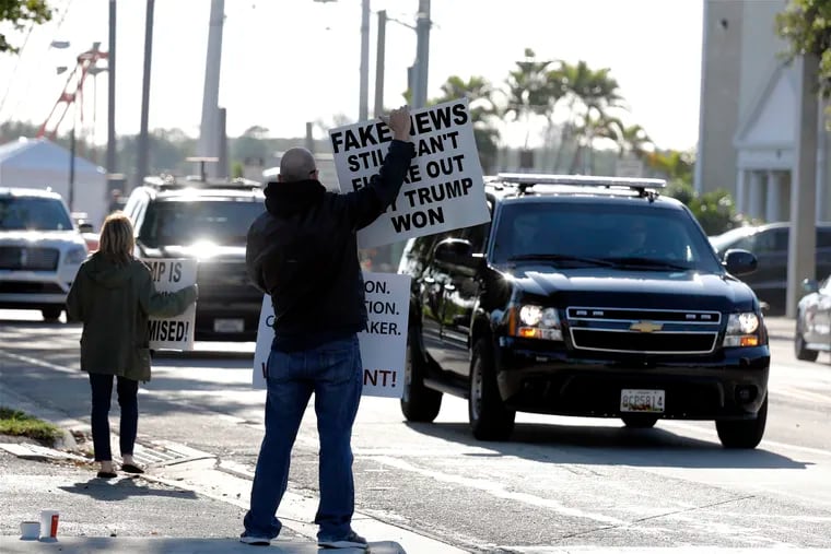 People hold signs as the motorcade of President Donald Trump passes on Saturday, March 23, 2019, in West Palm Beach, Fla. Special counsel Robert Mueller closed his long and contentious Russia investigation with no new charges, ending the probe that has cast a dark shadow over Trump's presidency.