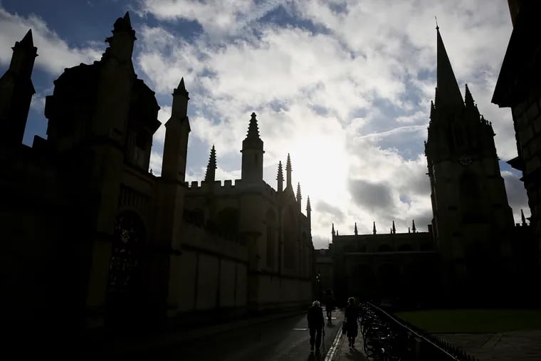 All Souls College, left, and the University Church of St. Mary the Virgin, right, are silhouetted against the morning sun at the University of Oxford in Oxford, England.