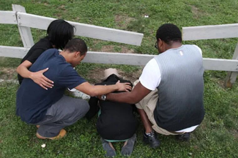 At the end of the vigil, family members including Kenya Boulware bowed at the site of where Moses Walker was murdered. ( RON CORTES / Staff Photographer ).