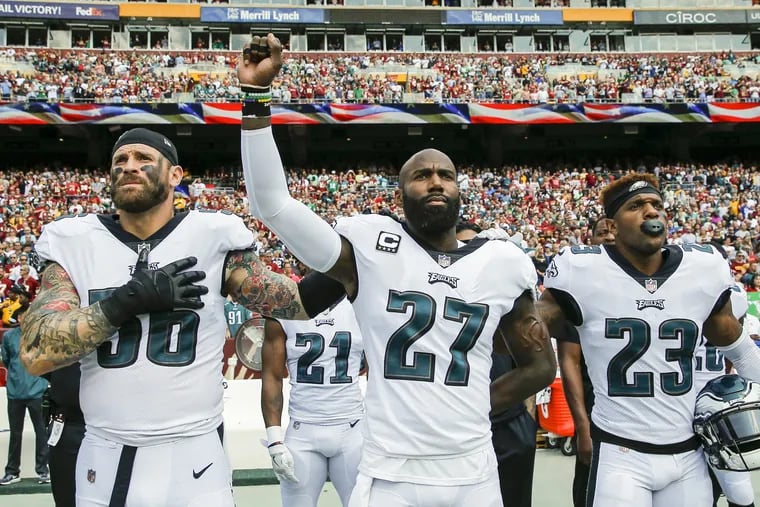 The Eagles' Malcolm Jenkins raises his fist as a form of protest prior to a game vs. the Redskins last year. He is joined by Chris Long (left) and Rodney McLeod. 