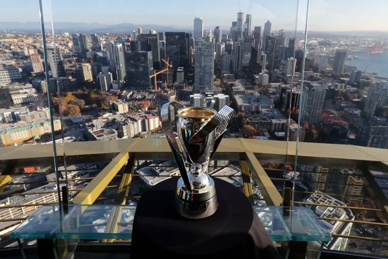 The MLS Cup trophy on display at the top of the Space Needle in Seattle, with the city's skyline in the background.
