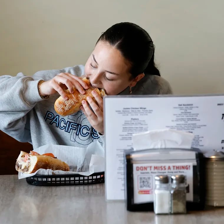 Jade Goffman eats the Thunderbird (T-Bird) Special Cheesesteak with American cheese, deluxe ham and sliced tomato at the Original Thunderbird Steakhouse & Catering in Broomall, PA on Monday, May 20, 2024.