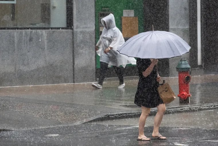 Rains falls as pedestrians walk past the corner of 16th and Chestnut Streets in Philadelphia.