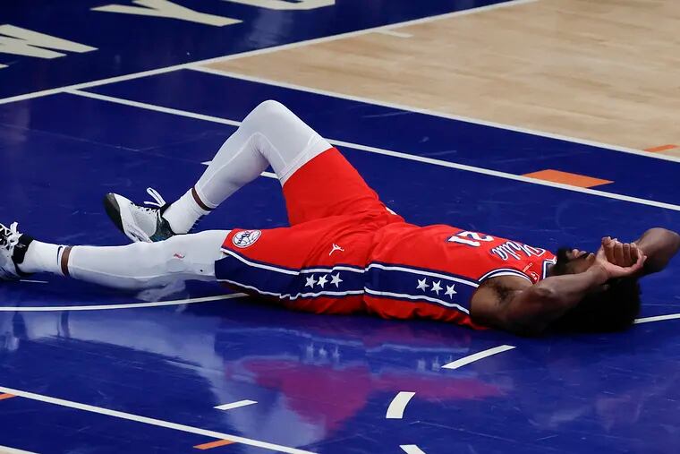 Sixers center Joel Embiid lays on the floor after injuring his knee against the New York Knicks in the first round of the NBA Eastern Conference playoffs on April 20.