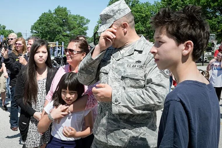 Air Force Sgt. Rafael Encinas, with his wife and children, gets emotional outside Evans Elementary School. Encinas was honored at the school's Memorial Day celebration Friday. (ED HILLE / Staff Photographer)