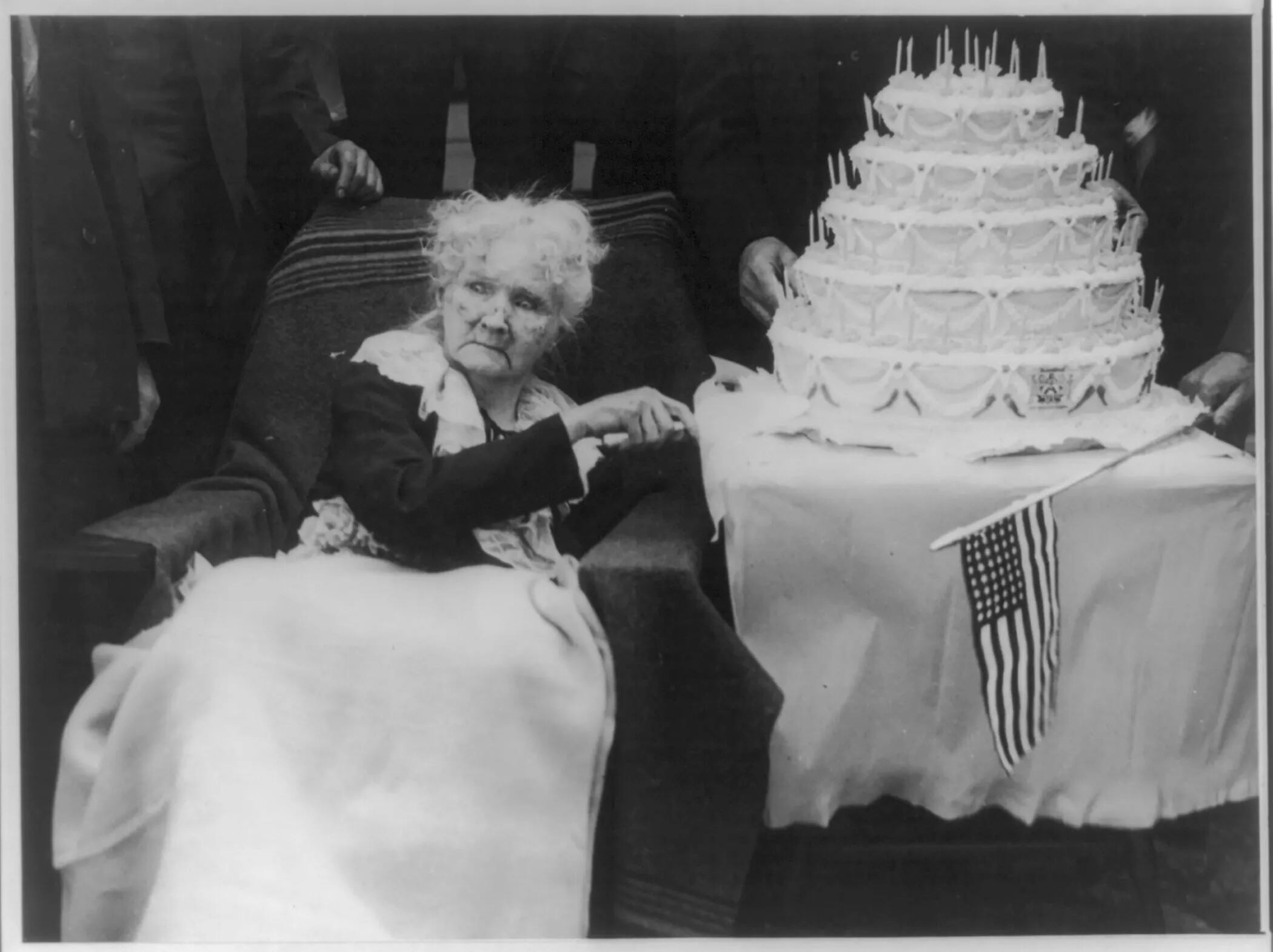Mary "Mother" (Harris) Jones, 1830-1930, half-length portrait, seated, facing left, about to cut a large birthday cake on her hundredth birthday anniversary in May 1930.