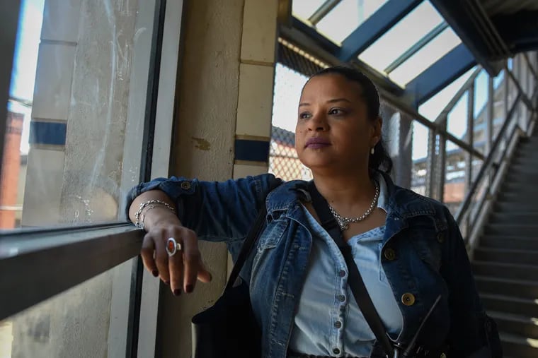 Roz Pichardo looks out the window at Kensington Avenue from inside the Somerset El station. Pichardo lives in Kensington and works in the harm reduction community in the neighborhood.