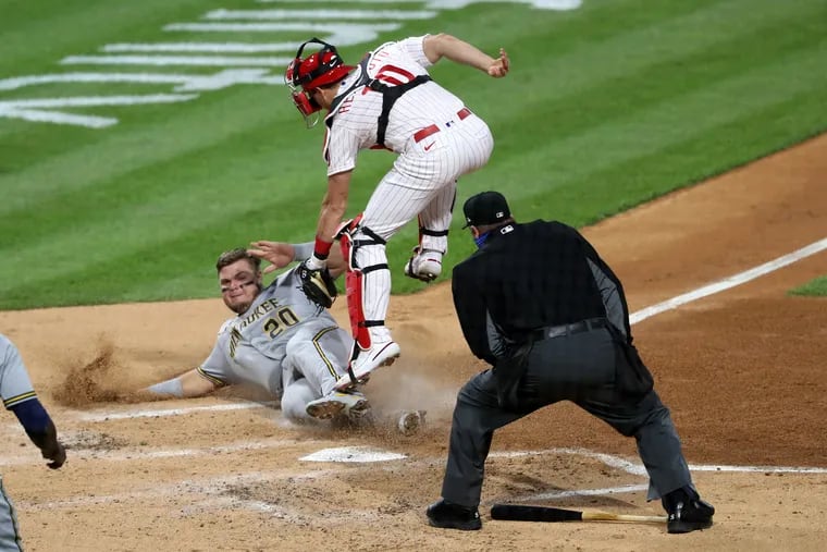 Phillies catcher J.T. Realmuto reaches down to tag the Milwaukee Brewers' Daniel Vogelbach on a play at the plate in the third inning Wednesday night at Citizens Bank Park. After being ruled safe on the field, Vogelbach was called out upon review.