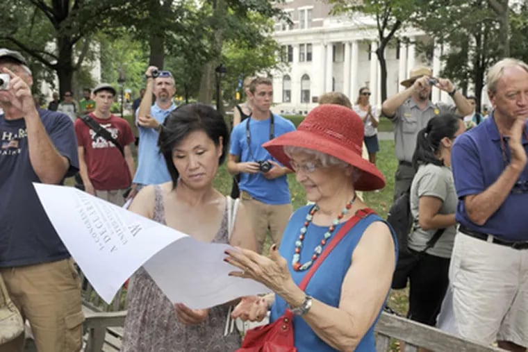 Mary Bristow (right) of Center City and Insook Avila of Bloomington, Ind., follow a reading of the Declaration. (Tom Gralish / Staff Photographer)