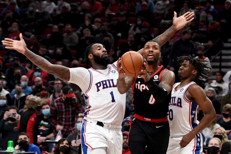 Portland Trail Blazers guard Damian Lillard, center, drives to the basket on Philadelphia 76ers center Andre Drummond, left, and guard Tyrese Maxey, right, during the second half of an NBA basketball game in Portland, Ore., Saturday.
