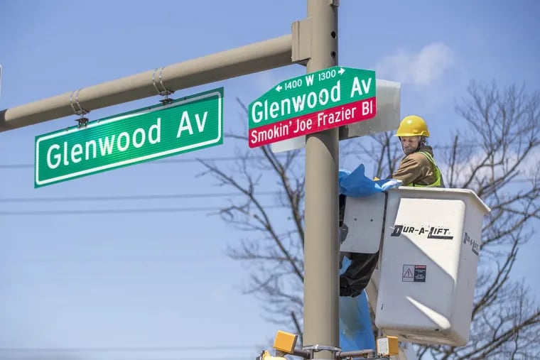 Elmer Heard, of the city’s traffic division, unveils the new sign on Glenwood Avenue honoring legendary boxer Joe Frazier on Wednesday.