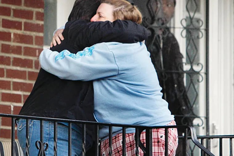 Two neighbors hug as police gather on the 300 block of Stevens Street after a woman and her adult son were found shot to death.  (Joseph Kaczmarek)