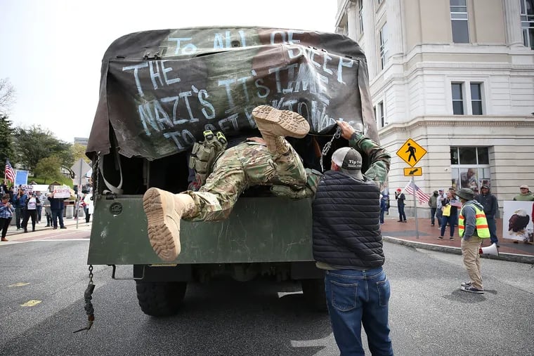 A militia member dives into the back of a truck after a protest outside the Capitol Complex in Harrisburg on April 20, 2020. They are calling for Gov. Tom Wolf to reopen the state's economy during the coronavirus outbreak.