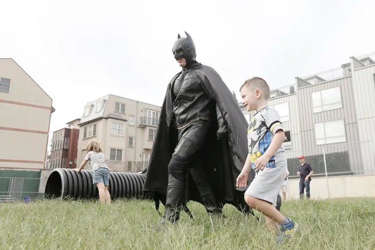 Batman, played by Andrew Arsenault of Let's Party Events, and Breck Dougherty are on their way to start a superhero game during Breck's fourth birthday party at Shot Tower playground in Queen Village.