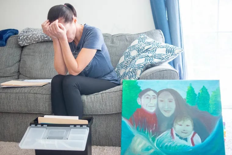 Becky Hofmann holds her hands over her face as she speaks about her late partner, Maddie, being shot to death by police during a wellness check. On the right is a painting showing their sons, with Maddie in the center. Maddie’s hand is shown on far left bottom of painting.