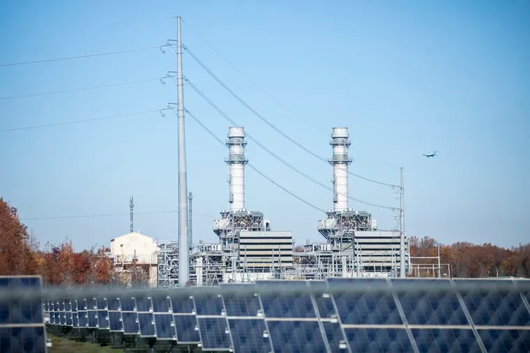 The West Deptford Energy LLC power station, fueled by natural gas, is viewed behind a field of solar panels in Paulsboro, N.J. Rising energy prices on the regional power grid are causing customer rates to increase Dec. 1 at many Pennsylvania electric utilities.