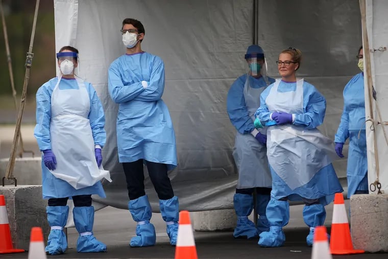 Medical workers wait for cars to pull up to the swabbing tent at a now-closed coronavirus testing site next to Citizens Bank Park in South Philadelphia on Friday, March 20, 2020.