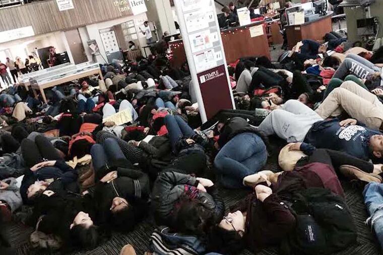 Temple students stage a second "die-in" of the day Thursday, surrounding the library’s circulation desk. Sofiya Ballin/Staff